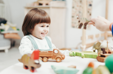 young girl playing with wooden toys with a teacher